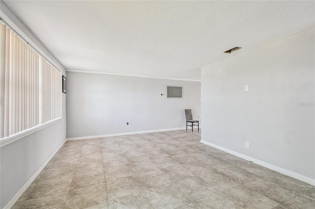 An empty room with light gray walls, large floor tiles, and a window with blinds — 13606 ALLYN DRIVE, HUDSON, FL