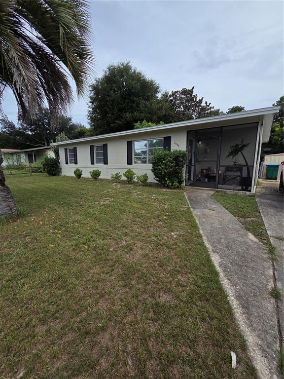 A living and dining area features wood-look tile flooring, a sectional sofa, and rustic chairs — 2433 ADAMS AVENUE, DELTONA, FL
