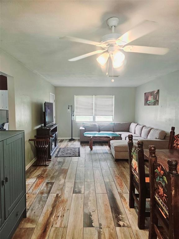 A bedroom features a bed with a built-in headboard, wood-look tile flooring, and a floor mirror — 2433 ADAMS AVENUE, DELTONA, FL