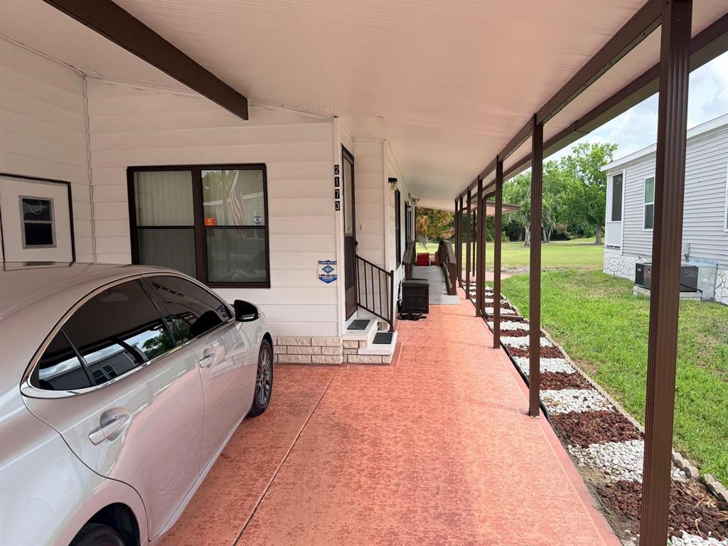 A silver car is parked under a covered carport next to a white mobile home — 2173 PEBBLE BEACH BOULEVARD, ORLANDO, FL