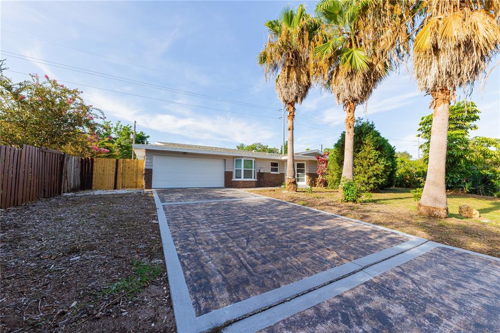 A single-story house with a paved driveway and three palm trees in the front yard — 1574 SOUVENIR DRIVE, CLEARWATER, FL