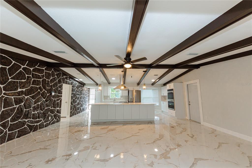 A kitchen with a large island, stone accent wall, and exposed dark wood ceiling beams — 1574 SOUVENIR DRIVE, CLEARWATER, FL
