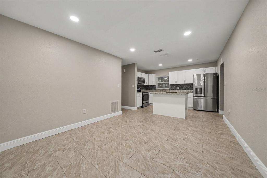 A kitchen with white cabinets, stainless steel appliances, and a small island on tiled floors — 1339 E JACKSON AVENUE, MOUNT DORA, FL