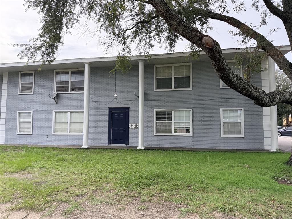 A two-story gray brick apartment building features white columns and a central dark blue door — 5328 WHITEWAY DRIVE, TEMPLE TERRACE, FL