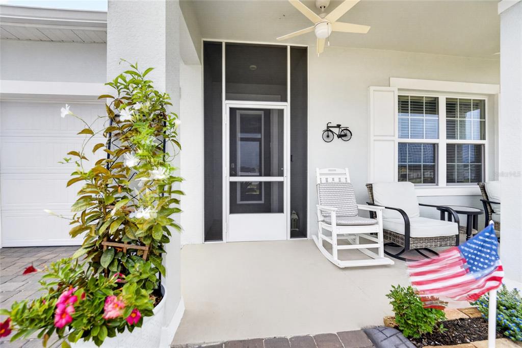 A covered front porch features a screen door, rocking chair, outdoor seating, and potted plants — 10859 SW 72ND CIRCLE, OCALA, FL
