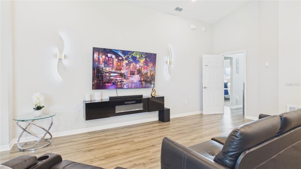 A living room features a wall-mounted television, a floating fireplace console, and dark leather furniture — 631 VISTA VIEW LANE, LAKE WALES, FL