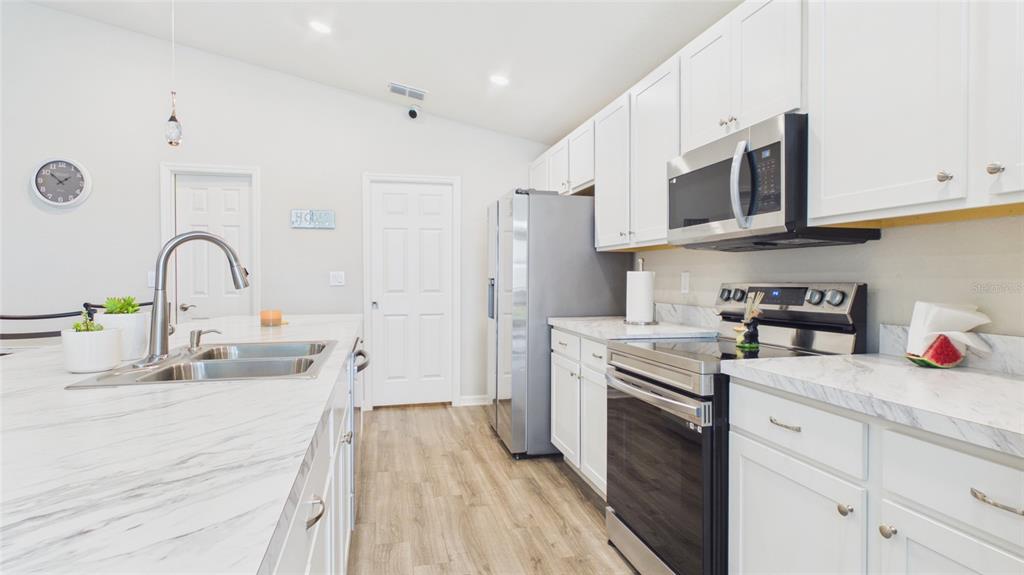 A modern kitchen features white cabinets, stainless steel appliances, and a marble-patterned island countertop — 631 VISTA VIEW LANE, LAKE WALES, FL