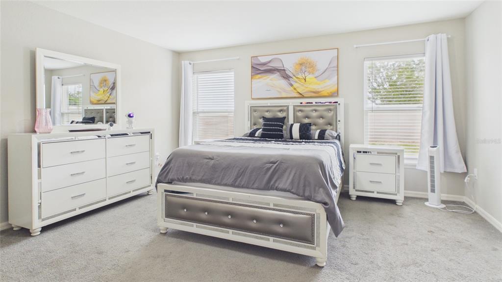 A bedroom features a bed with a tufted headboard, matching white furniture, and gray carpeting — 631 VISTA VIEW LANE, LAKE WALES, FL