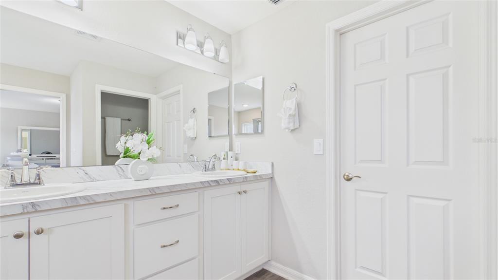 A bathroom features a double vanity with marble-look countertops, white cabinetry, and a large mirror — 631 VISTA VIEW LANE, LAKE WALES, FL
