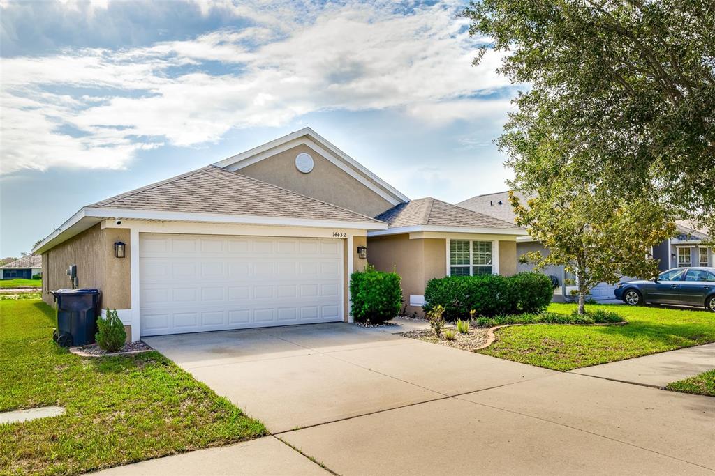 A tan single-story house with a two-car garage and a concrete driveway — 14432 BARLEY FIELD DRIVE, WIMAUMA, FL