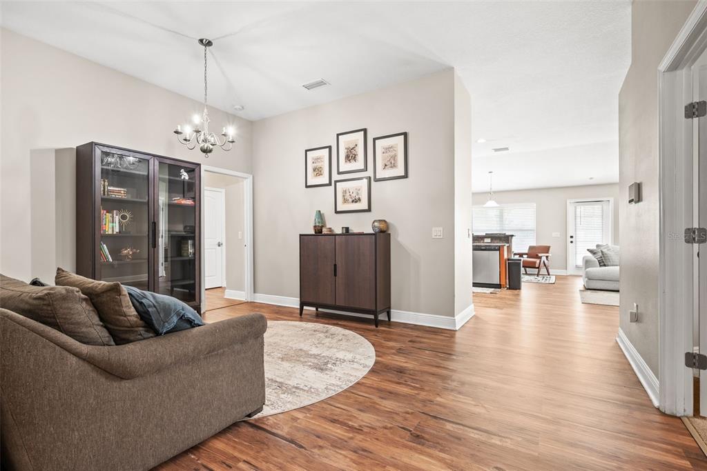 A living area with wood-look flooring, a dark wood cabinet, and a glass-front display case — 14432 BARLEY FIELD DRIVE, WIMAUMA, FL
