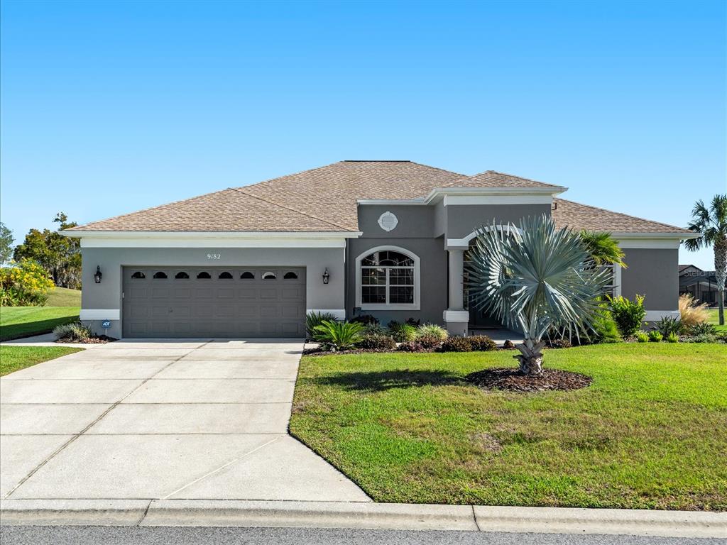 A single-story gray house with a two-car garage and a landscaped front yard — 9182 TARLETON CIRCLE, WEEKI WACHEE, FL