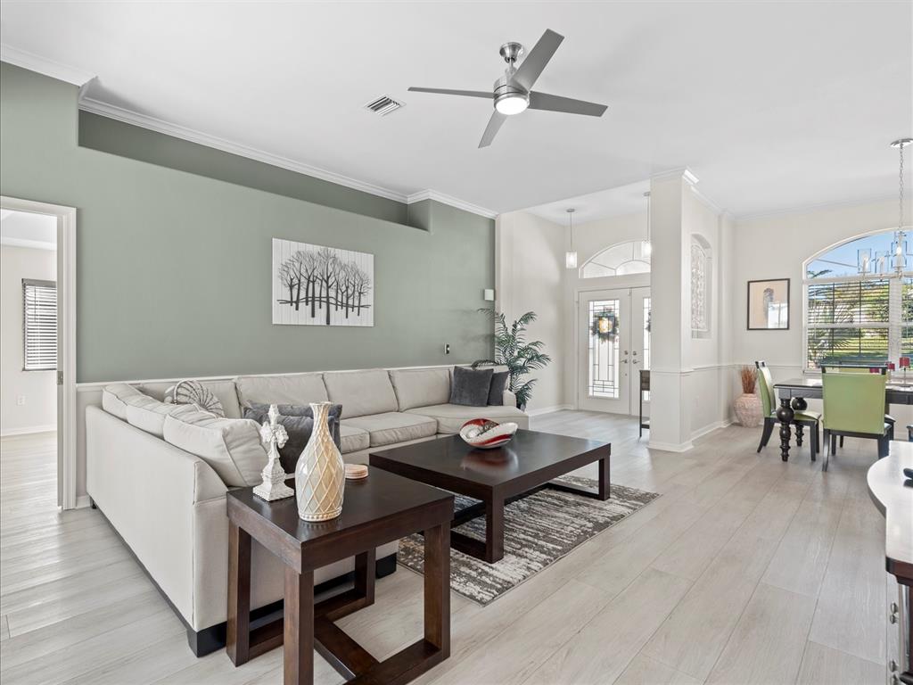 A living room features a light green accent wall, sectional sofa, and wood-toned flooring — 9182 TARLETON CIRCLE, WEEKI WACHEE, FL
