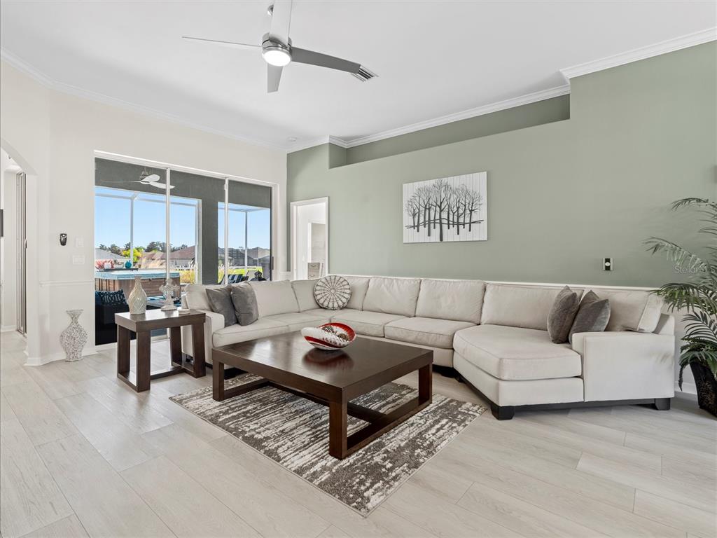 A living room features a large sectional sofa, a dark wood coffee table, and light flooring — 9182 TARLETON CIRCLE, WEEKI WACHEE, FL