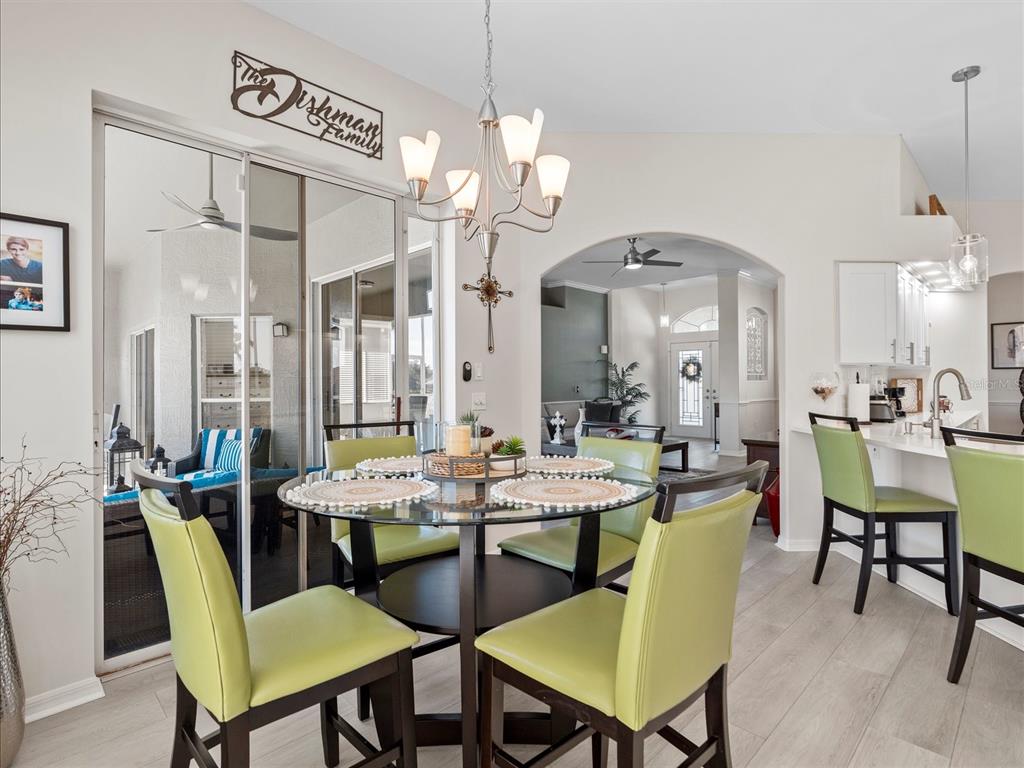 A dining area features a glass-topped table, lime green chairs, and a chandelier — 9182 TARLETON CIRCLE, WEEKI WACHEE, FL