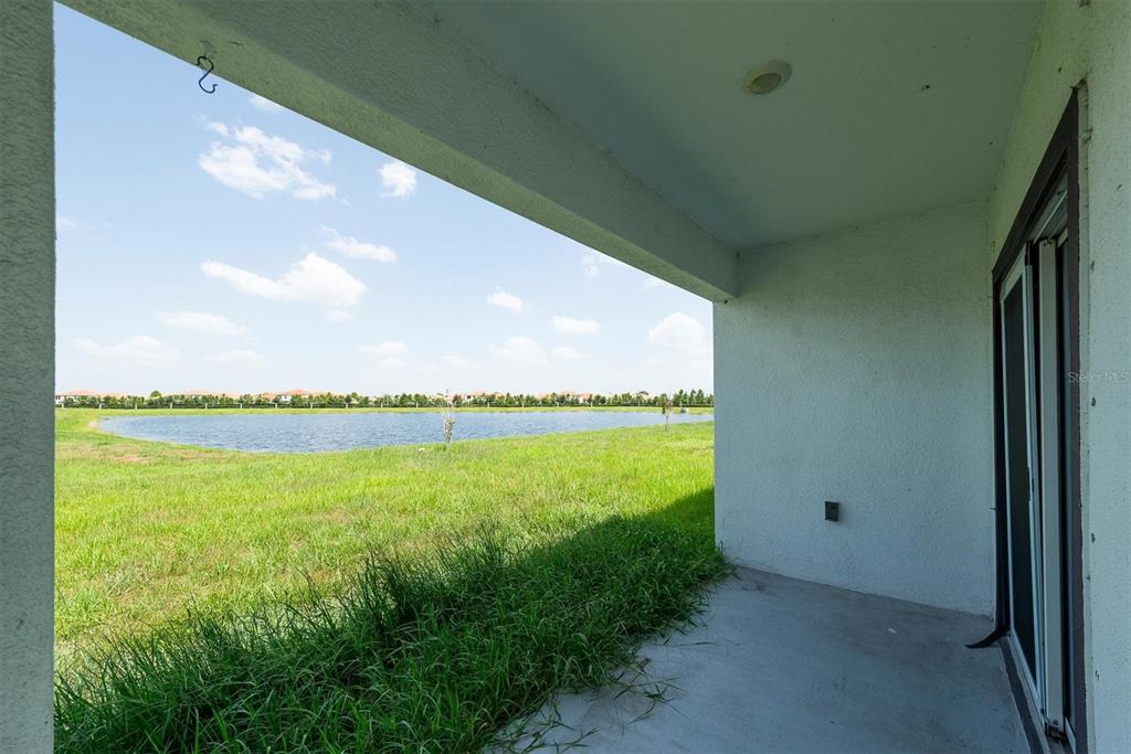 A covered concrete patio overlooks a grassy lawn and a small lake — 17066 OVAL RUM DRIVE, WIMAUMA, FL