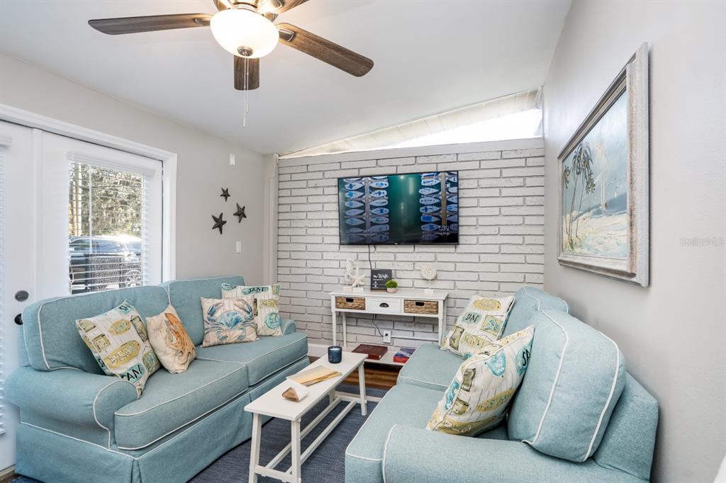 A living room features two light blue sofas, a white brick wall, and a ceiling fan — 2213 WASON ROAD UNIT 1, SARASOTA, FL