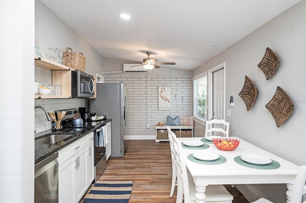 A kitchen and dining area with white cabinets, a brick wall, and a dining table — 2213 WASON ROAD UNIT 1, SARASOTA, FL