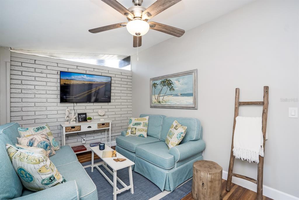 A living room features two light blue sofas, a white coffee table, and a brick wall — 2213 WASON ROAD UNIT 1, SARASOTA, FL