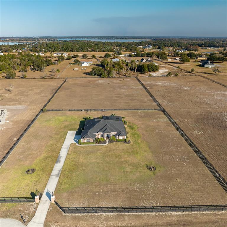An aerial view shows a single-story brick house centered on a large, fenced rural lot — 29222 CAN DO LANE, TAVARES, FL