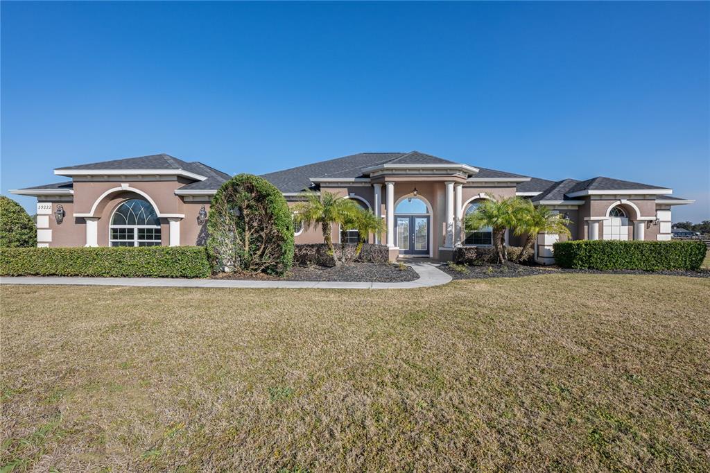 A single-story stucco house with a hip roof, arched windows, and a columned entryway — 29222 CAN DO LANE, TAVARES, FL