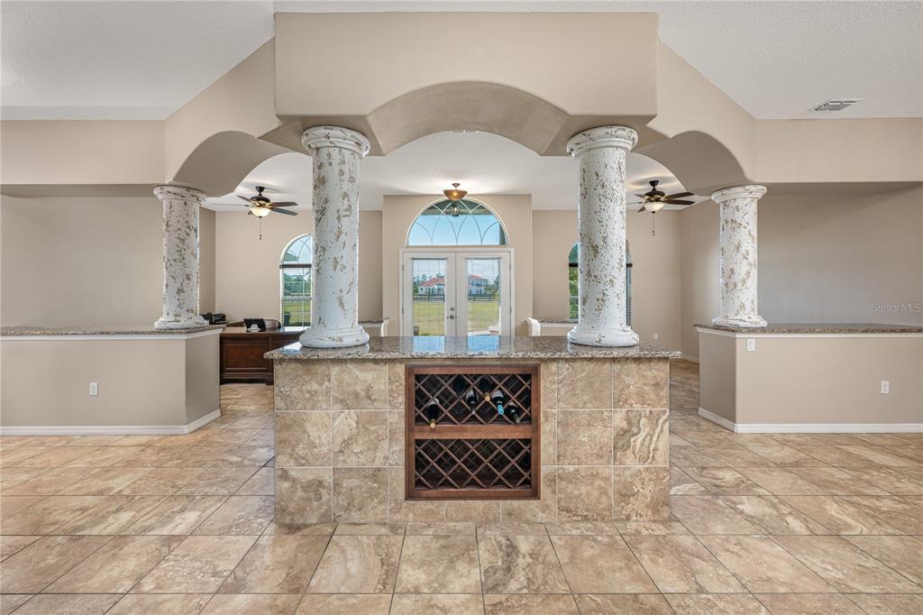 A room features a central stone-tiled bar with a wine rack and decorative white columns — 29222 CAN DO LANE, TAVARES, FL