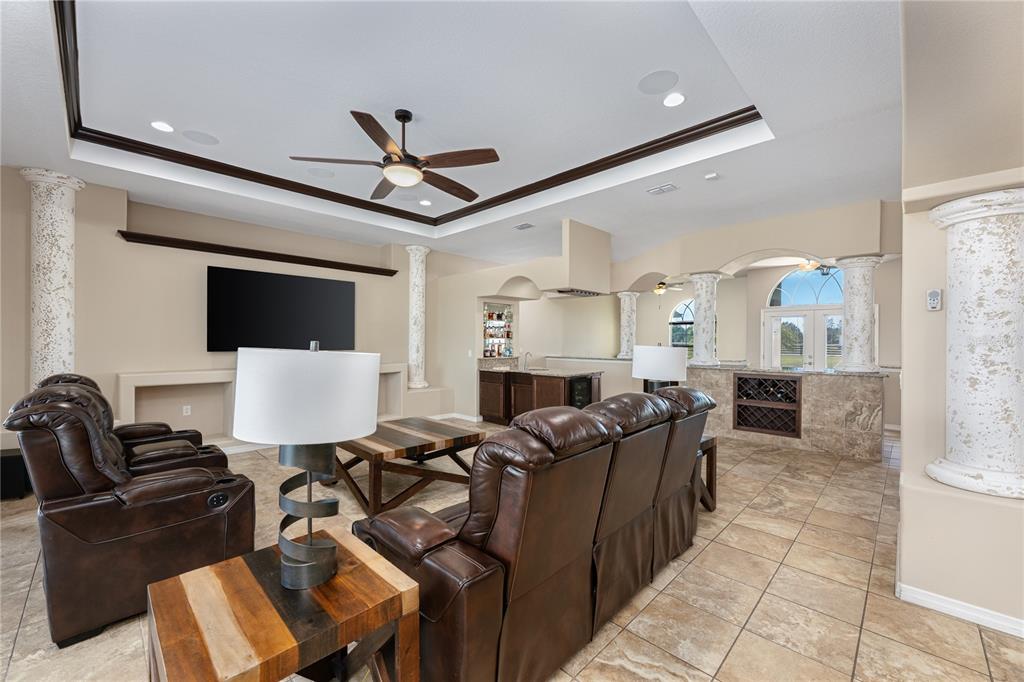 A living room features leather recliners, a bar area, and decorative columns under a tray ceiling — 29222 CAN DO LANE, TAVARES, FL
