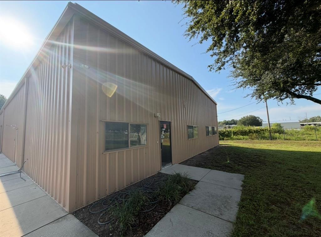 A tan metal-sided commercial building with a glass door and windows sits on a concrete walkway — 483 NW 68TH AVENUE, OCALA, FL