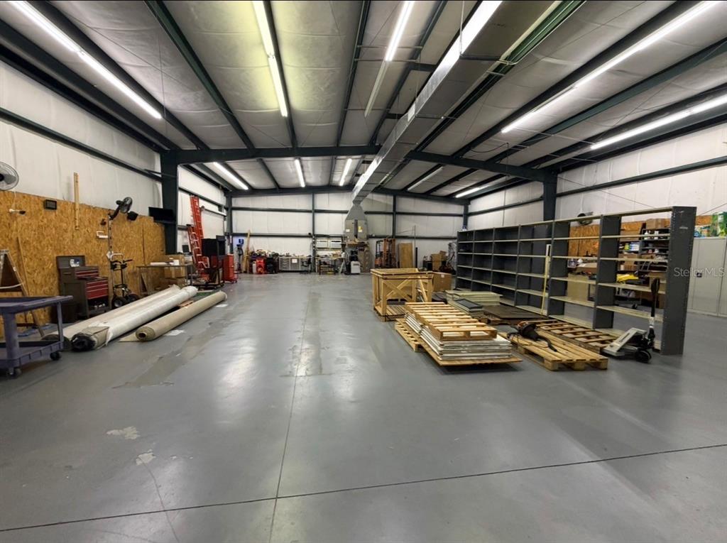 A large, open warehouse space with concrete floors, metal walls, and industrial shelving units — 483 NW 68TH AVENUE, OCALA, FL