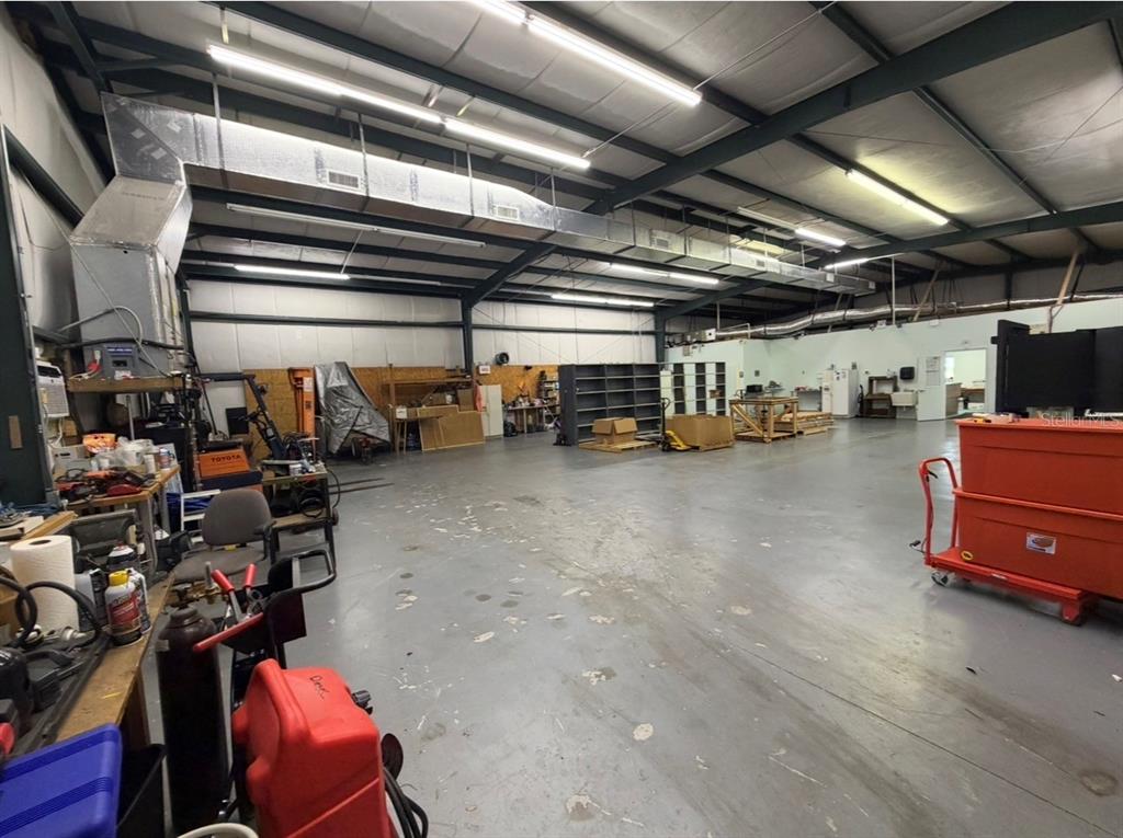 A large, open industrial warehouse space with concrete floors, exposed metal beams, and overhead lighting — 483 NW 68TH AVENUE, OCALA, FL