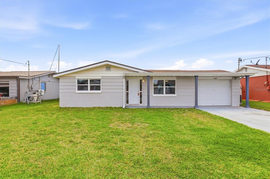 A single-story house with light gray siding, a white front door, and an attached garage — 13603 BRITTON DRIVE, HUDSON, FL