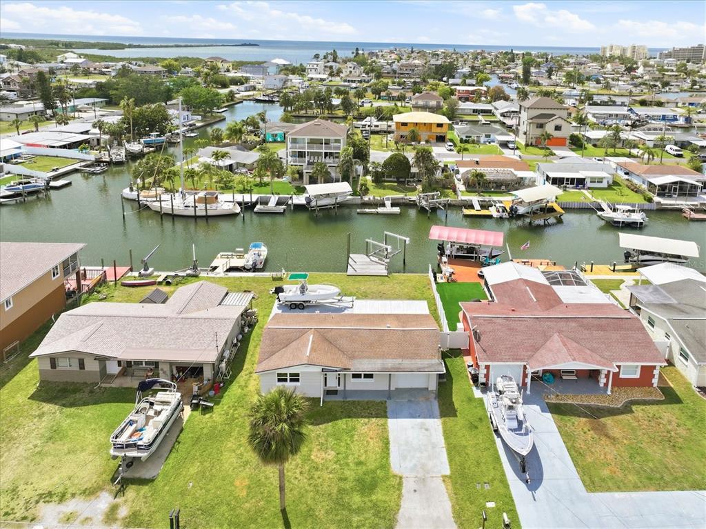 An aerial view shows three waterfront houses with boat docks and boats in a canal — 13603 BRITTON DRIVE, HUDSON, FL