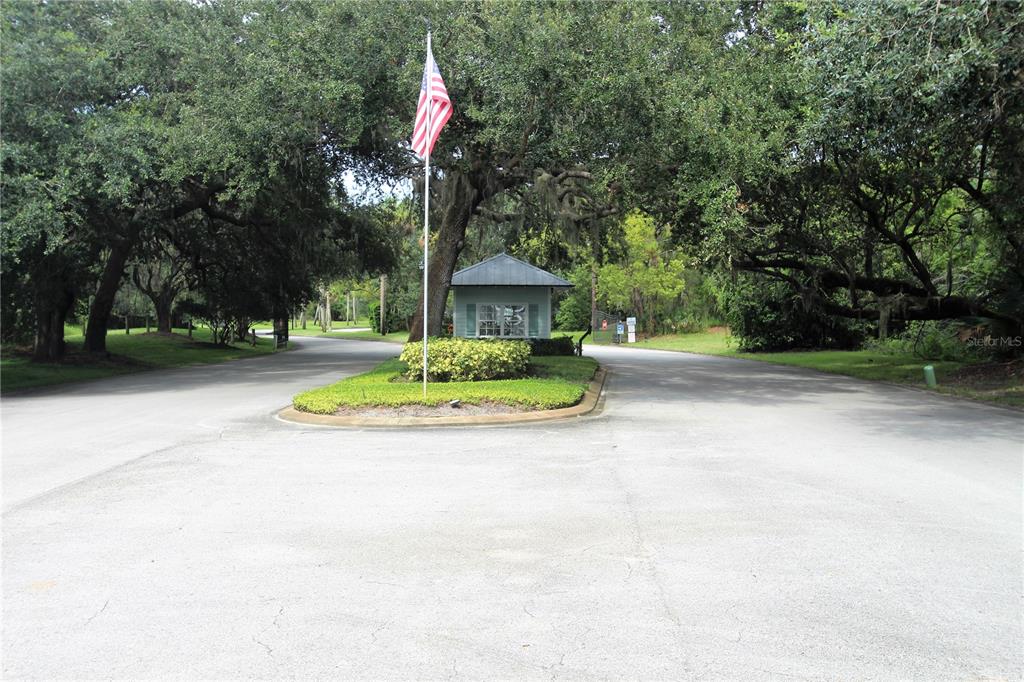 An aerial view shows a suburban street with several houses, mature trees, and a pond — 498 SIOUX BOULEVARD, OAK HILL, FL