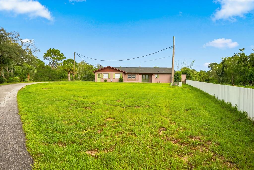 A single-story house with a pink exterior sits on a large, grassy lot — 9550 PURDY STREET, SPRING HILL, FL