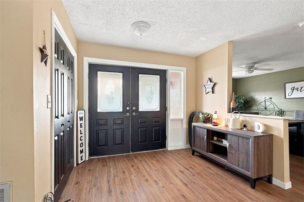 An entryway features a dark double door, wood-look flooring, and a wooden console table — 9550 PURDY STREET, SPRING HILL, FL