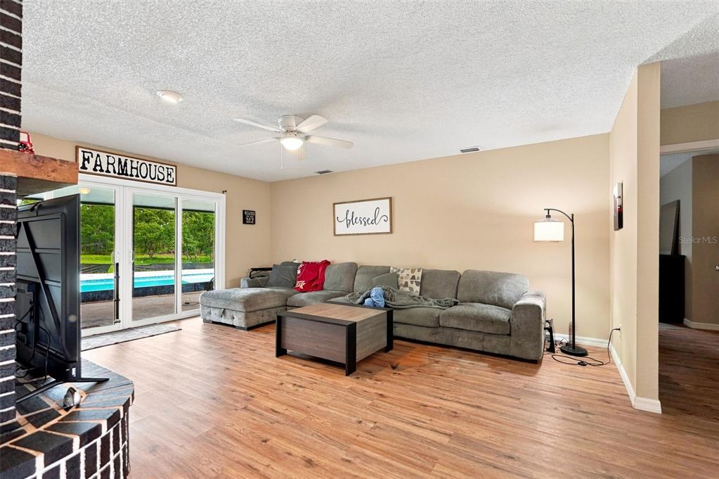 A living room features wood-look flooring, a gray sectional sofa, and a sliding glass door — 9550 PURDY STREET, SPRING HILL, FL
