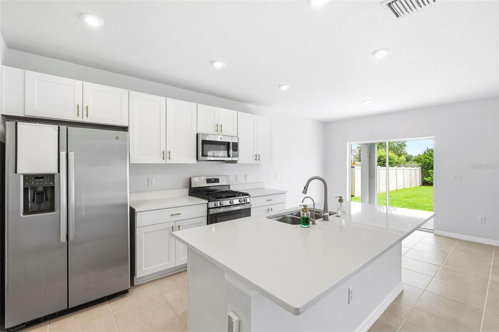 A kitchen with white cabinets, stainless steel appliances, a center island, and a sliding door — 6271 SPRINGMONT LOOP, PALMETTO, FL