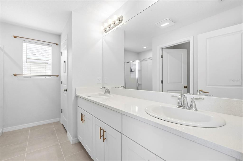 A bright bathroom features a white double vanity with quartz countertops and a large mirror — 6271 SPRINGMONT LOOP, PALMETTO, FL