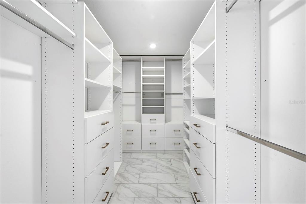 A walk-in closet features white custom shelving, drawers, and marble-look tile flooring — 6271 SPRINGMONT LOOP, PALMETTO, FL