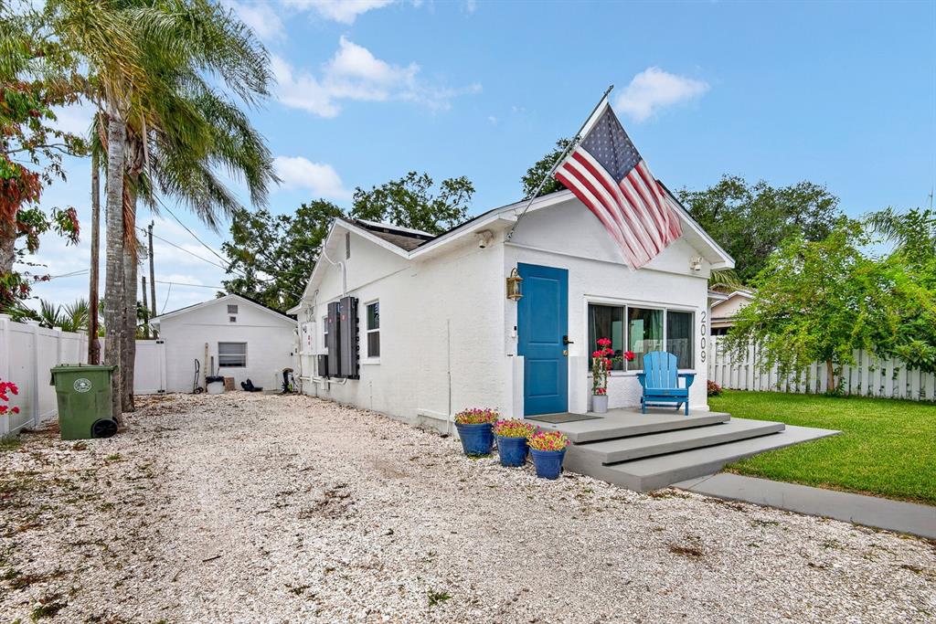 A white cottage with a blue door, an American flag, and a gravel driveway — 2009 1ST AVENUE E UNIT B, BRADENTON, FL