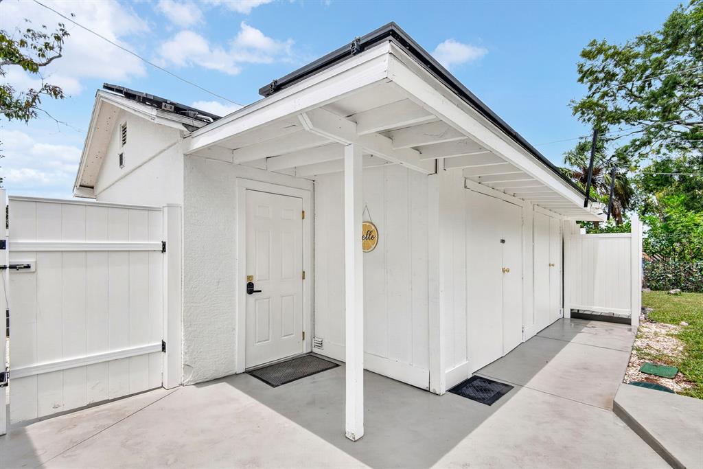 A white exterior building features a covered porch, a single door, and two storage closets — 2009 1ST AVENUE E UNIT B, BRADENTON, FL
