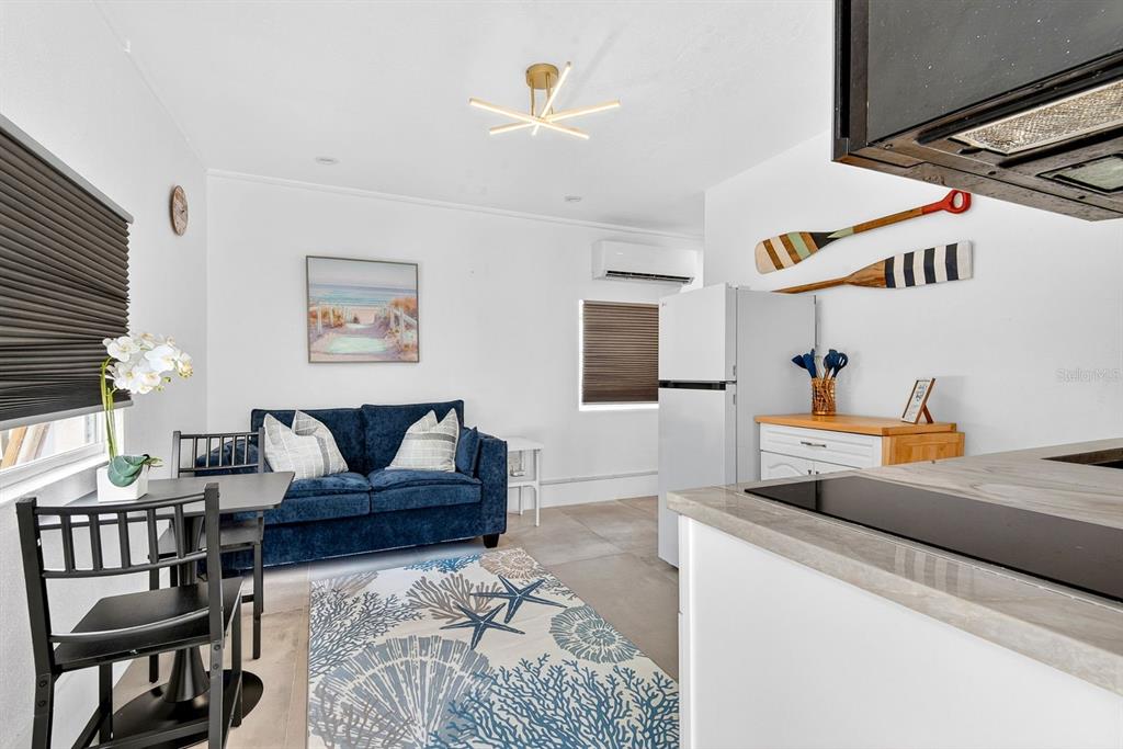 A small living room and kitchen area features a blue sofa, dining table, and rug — 2009 1ST AVENUE E UNIT B, BRADENTON, FL