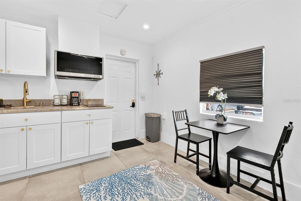 A small kitchen features white cabinets, a dining table with two chairs, and a door — 2009 1ST AVENUE E UNIT B, BRADENTON, FL
