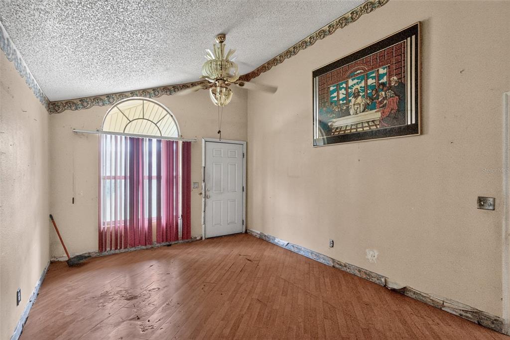 An empty room with wood-look flooring, a ceiling fan, a white door, and a wall painting — 1301 W 11TH STREET, SANFORD, FL