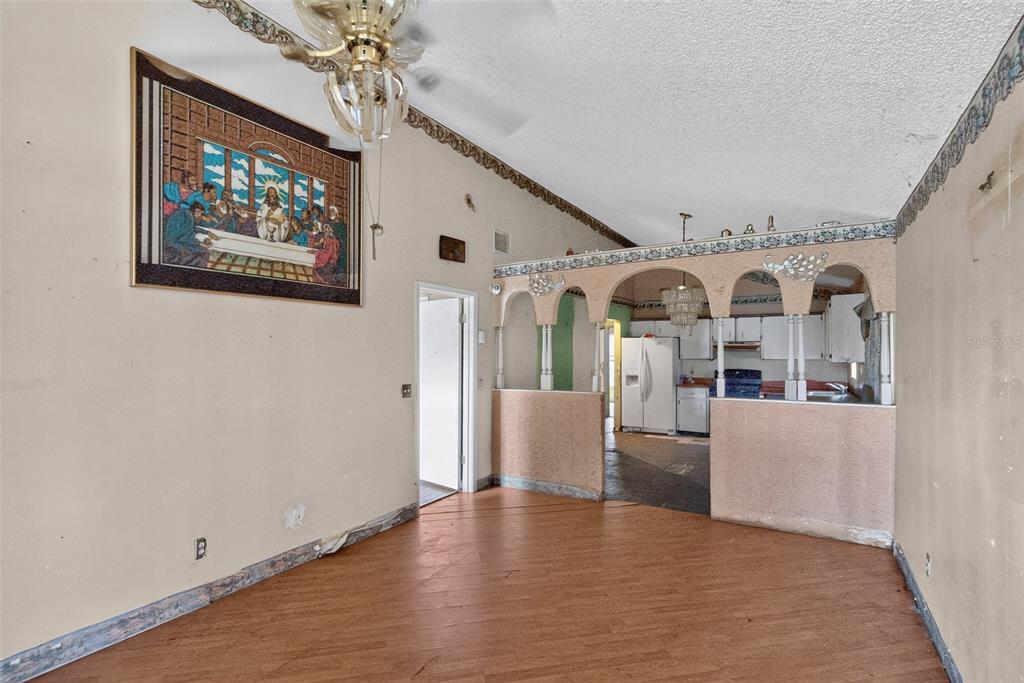 A living room with wood-look flooring, a vaulted ceiling, and an arched pass-through to the kitchen — 1301 W 11TH STREET, SANFORD, FL
