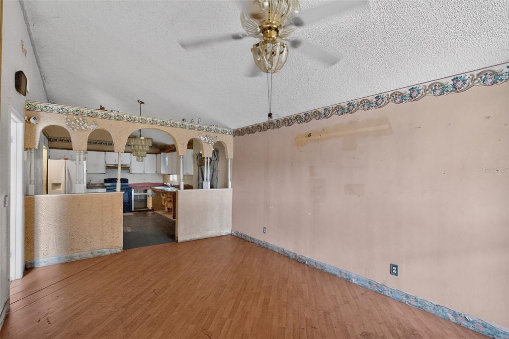 A living room with wood-look flooring, a ceiling fan, and an arched partition to the kitchen — 1301 W 11TH STREET, SANFORD, FL