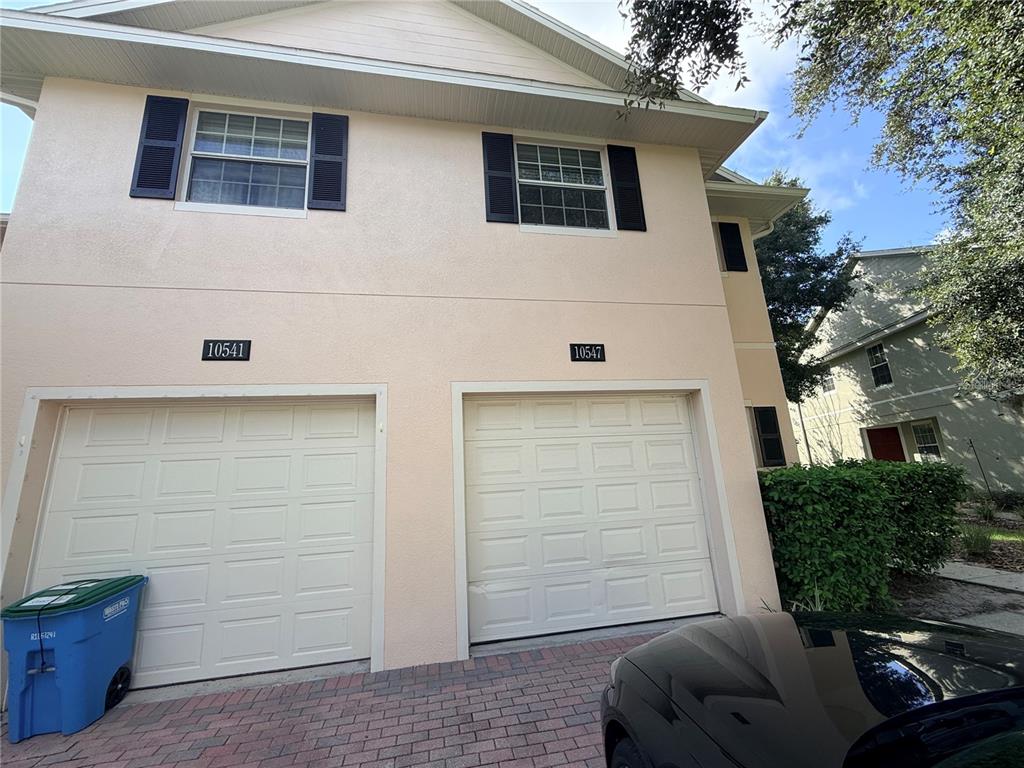 The exterior of a two-story duplex features two garage doors and a brick driveway — 10547 REGENT SQUARE DRIVE UNIT 1008, ORLANDO, FL