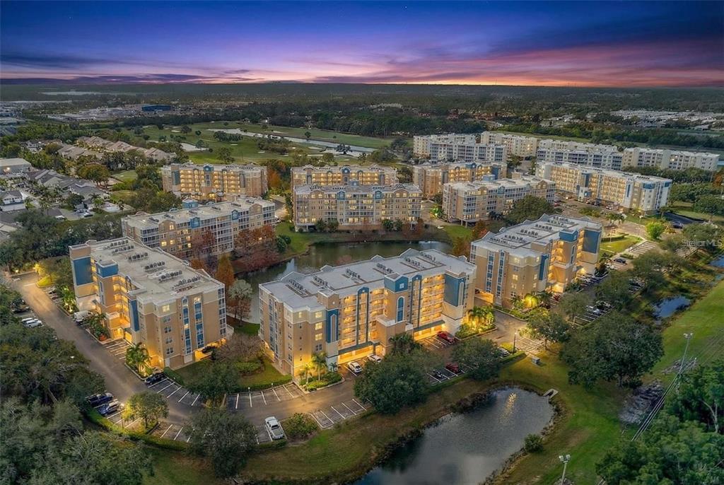 An aerial view of several multi-story apartment buildings surrounding a small lake at sunset — 960 STARKEY ROAD UNIT 3501, LARGO, FL