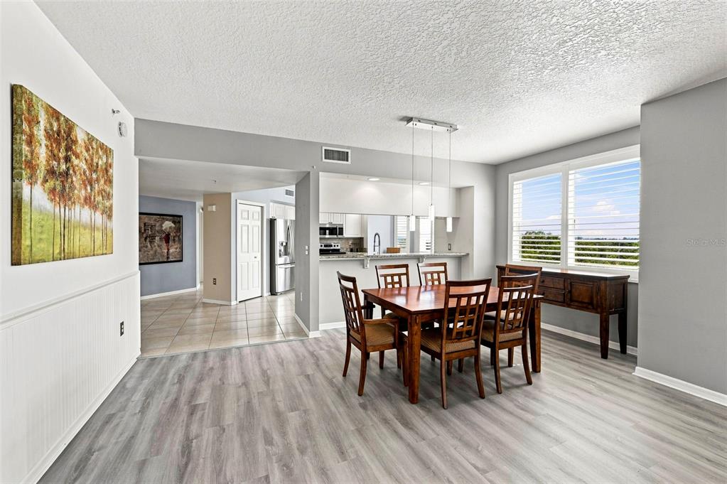 A dining area with wood flooring, a wooden table, and an open kitchen with bar seating — 960 STARKEY ROAD UNIT 3501, LARGO, FL