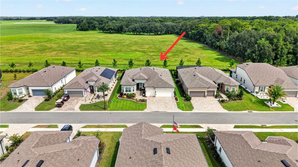 An aerial view shows a row of suburban houses bordering a large, open green field — 5235 SW 88TH CIRCLE, OCALA, FL